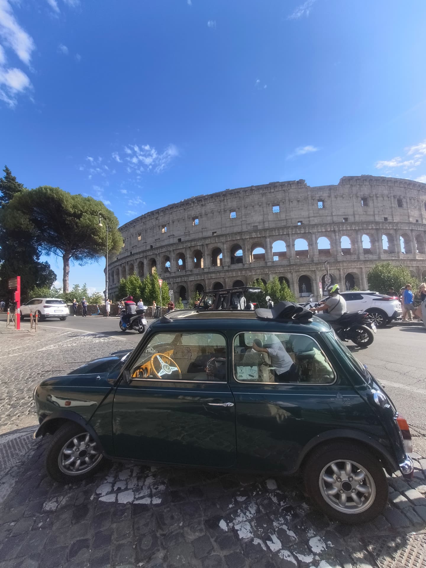 The 1995 Rover Mini Classic parked on the cobblestones in front of the Colosseum, Rome